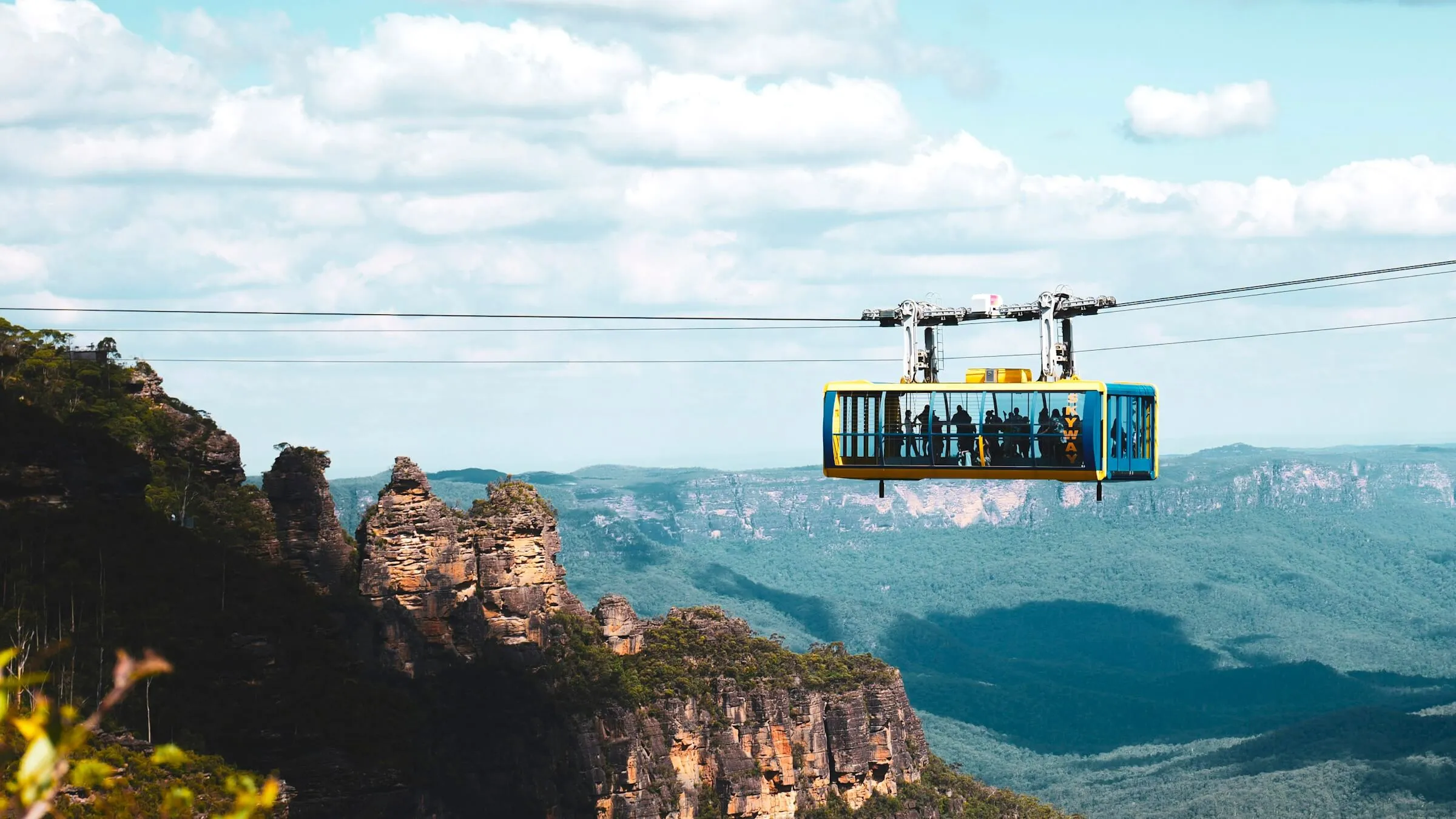 Yellow-and-blue Scenic Skyway cabin crossing the Jamison Valley beside the Three Sisters